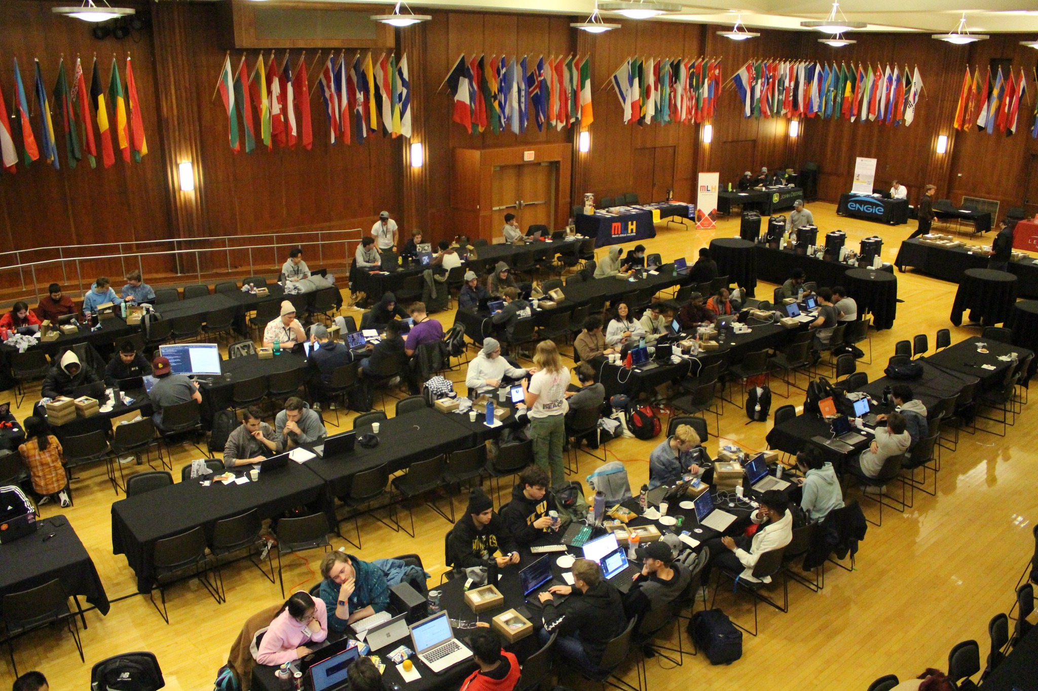 A room full of people and a corner where sponsors have tables setup
